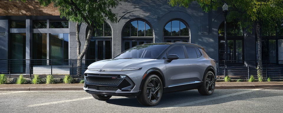 Front Three Quarters of a Grey 2025 Equinox EV Next to a Building