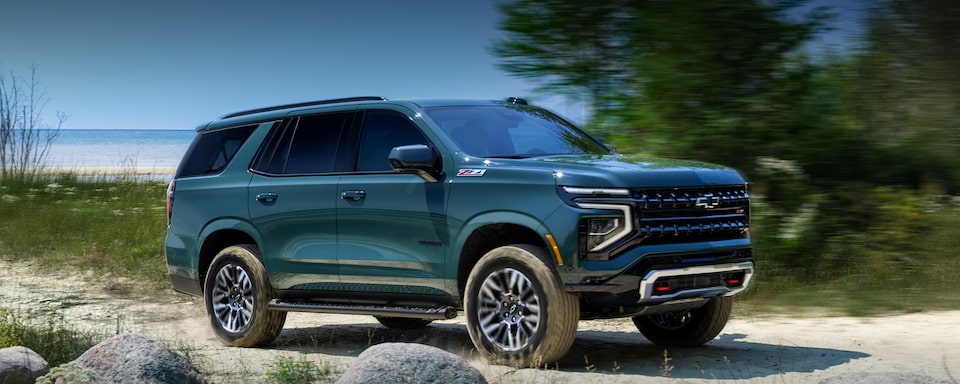 Front Side View of the 2025 Chevrolet Tahoe SUV Driving on a Gravel Path